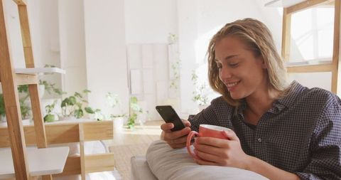 Woman Relaxing at Home with Smartphone and Tea