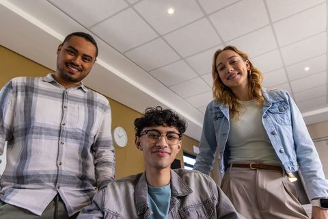 Smiling diverse students collaborating in classroom wearing denim jackets and glasses