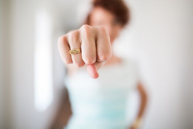 Close-up of clenched fist with focus on a gold ring inscribed with the word 'Faith'. Can be used to symbolize empowerment, strength, confidence, and spirituality. Suitable for religious contexts, motivational posters, or personal empowerment themes.