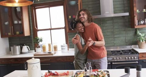 Happy Couple Embracing While Cooking in a Modern Kitchen Setting