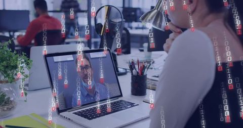 Professional woman joining video call on laptop in open office with digital binary overlay
