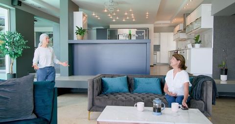 Senior female friends enjoy relaxing conversation in shared living space