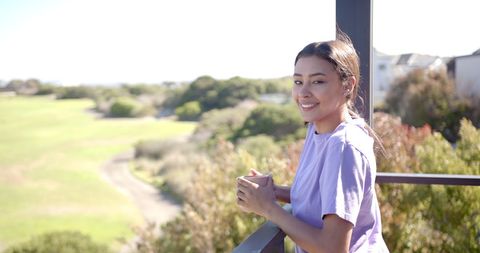Smiling Woman Enjoys Scenic View from Balcony with Coffee