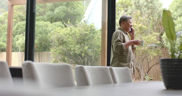 Man talking on phone in modern dining room with large windows - Download Free Stock Images Pikwizard.com