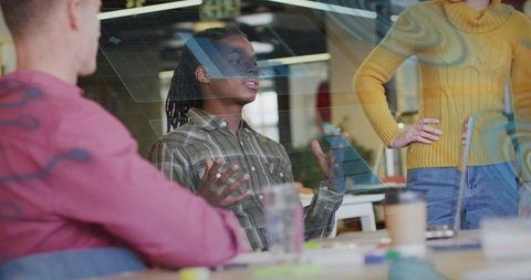 Team presenting and brainstorming through glass partition in modern open-plan workspace