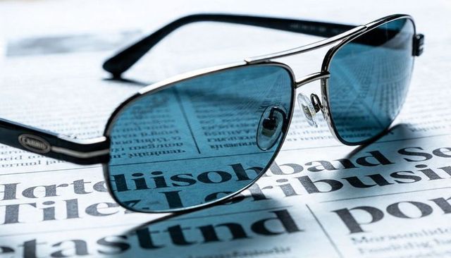 Resting Aviator Sunglasses Casting Cyan Tint Over Newspaper Closeup, Metallic Double Bridge