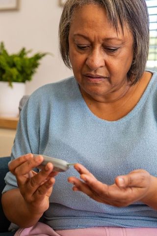 Senior woman testing blood sugar at home for diabetes care