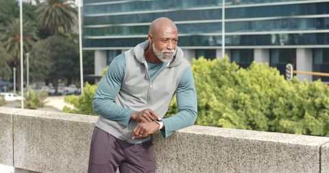 Mature African American Man Checking Smartwatch Leaning on Urban Overpass in Athleisure