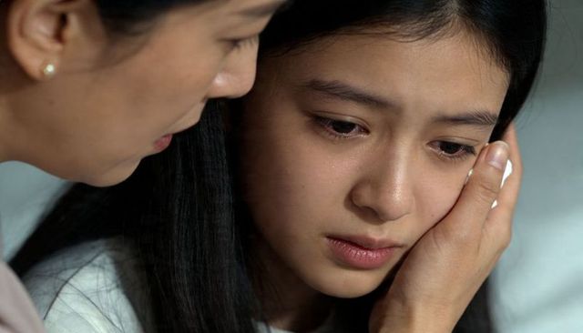 Mother comforting tearful asian teen daughter during emotional closeup moment of empathy
