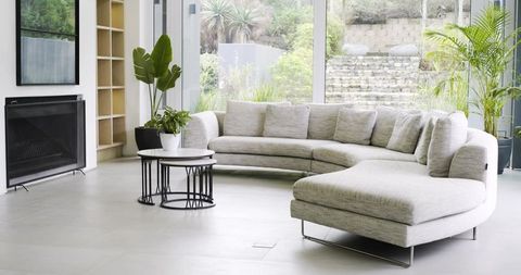 Curved light-gray sectional sofa featuring chaise in bright modern living room