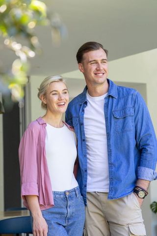 Young couple smiling and looking toward future at modern home entrance
