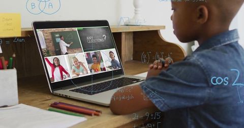 Young boy engaged in online math class with laptop and books