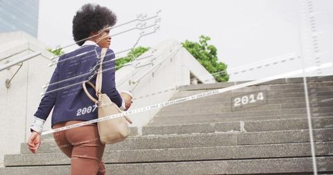 Businesswoman climbing urban stairs carrying coffee and satchel with digital data overlay