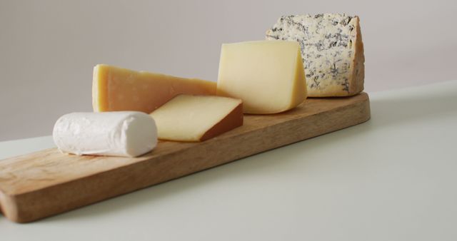 Selection of cheese varieties placed on wooden board, ranging in texture and flavor. Useful for articles or content about culinary arts, gourmet foods, wine pairings, appetizers, and food presentations