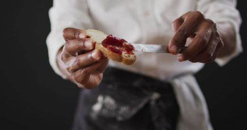 Close-up of cook spreading jam on bread slice