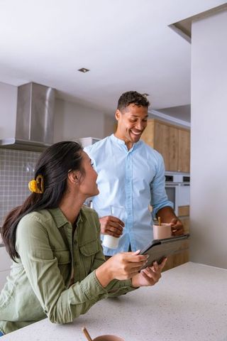 Happy Couple Reviewing Tablet in Modern Kitchen Setting