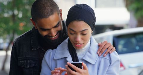 Happy Biracial Couple Using Smartphone on City Street
