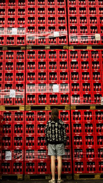 Person Standing in Front of Stacked Red Beverage Crates in Warehouse - Download Free Stock Images Pikwizard.com