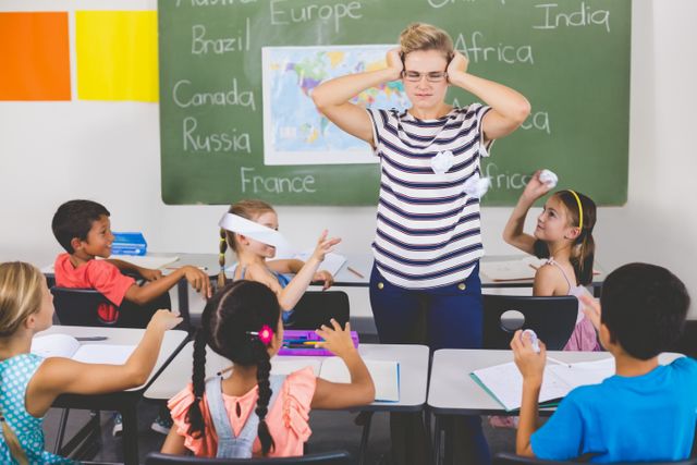 This image depicts a classroom scene where a teacher appears frustrated as students throw paper balls. Ideal for illustrating challenges in education, classroom management, and playful student behavior. Useful for educational blogs, articles on teaching strategies, and school-related content.