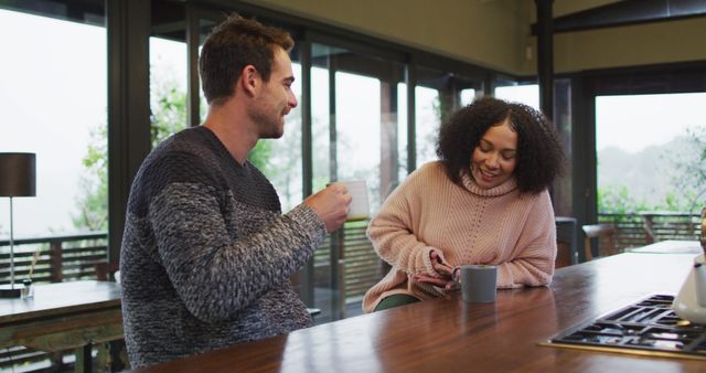 Happy diverse couple talking and drinking coffee in kitchen - Download Free Stock Photos Pikwizard.com