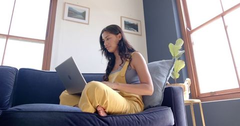 Biracial Teenage Girl Studying on Sofa with Laptop at Home