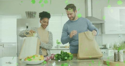 Couple unpacking groceries at modern kitchen island using reusable bags preparing meal