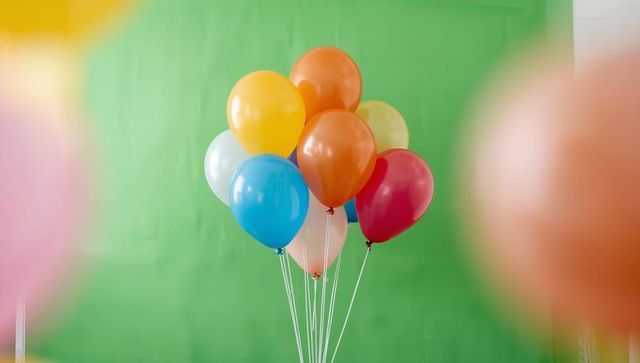 Colorful helium balloons over green backdrop for festive celebrations