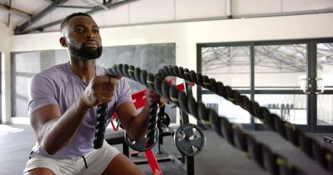 Determined African American Man Using Battle Ropes in Gym