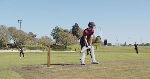 Cricketer in Full Gear Batting on Sports Field