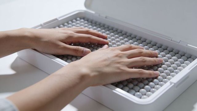 Hands pressing textured bead therapy tray for sensory stimulation and relaxation