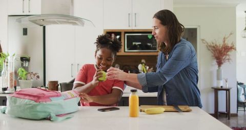 Mother and Daughter Packing Lunch Together in Modern Kitchen