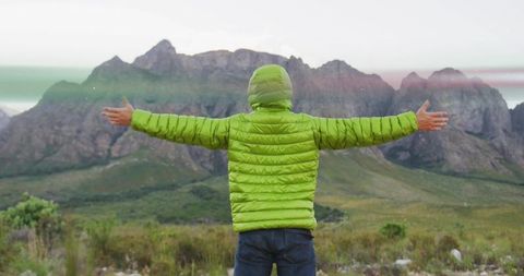 Hiker embracing nature standing in foothills against breathtaking mountain range