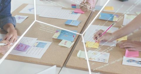 Team collaborating on UX planning with sticky notes, sketches and wireframes on corkboards