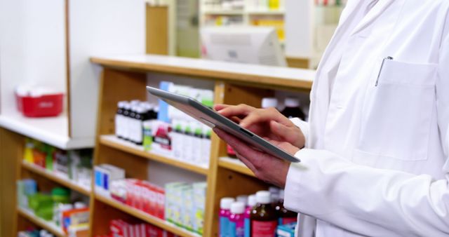 Pharmacist in white coat using tablet while managing inventory in a modern pharmacy. Background filled with various medications and supplies on shelves. Perfect for illustrating technology in healthcare, modern pharmaceutics, and medical professions, as well as pharmacy management software.