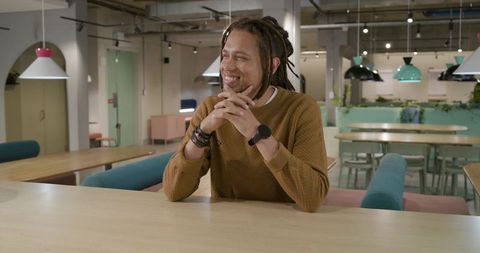 African american man smiling at coworking lounge table, collaborating in modern workspace