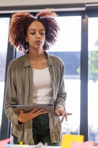 Confident Professional Woman Presenting Digital Ideas in Modern Office
