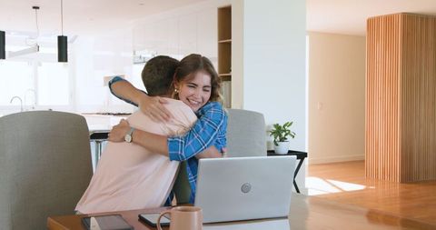 Couple celebrating success with papers near laptop