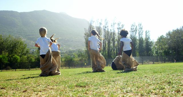 Children are engaging in a sack race on a sunny day in a grassy field, with copy space - Download Free Stock Photos Pikwizard.com