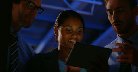 Diverse Business Team Collaborates with Digital Tablet at Night