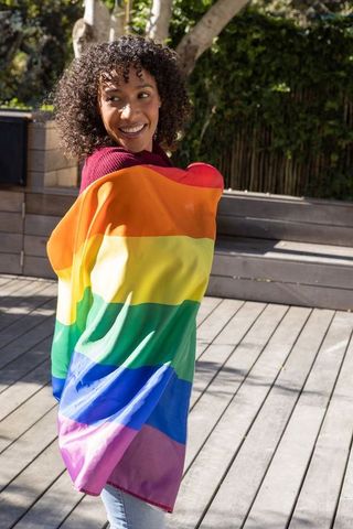 Joyful Woman Celebrating Pride with Rainbow Flag on Sunny Deck