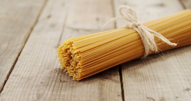 Bundle of Uncooked Spaghetti Tied with Twine on Wooden Table - Download Free Stock Images Pikwizard.com