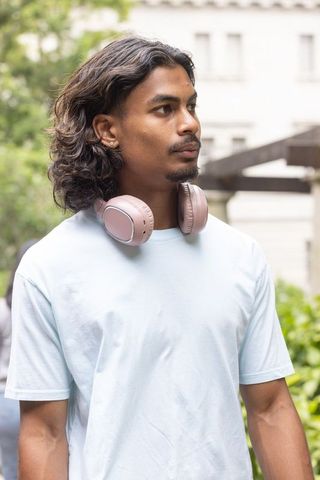 African american man standing in urban courtyard wearing pink headphones, contemplative portrait