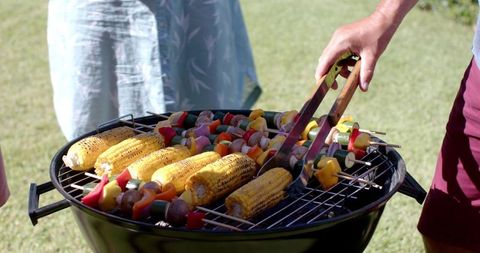 Seniors Grilling Vegetable-Meat Skewers and Corn Outdoors