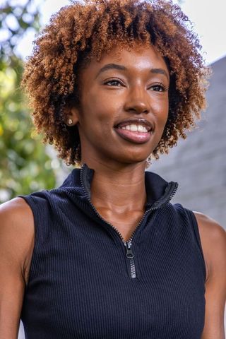 Confident african american woman smiling outdoors wearing black zip-front top portrait