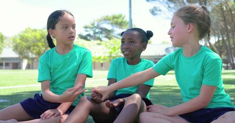 Girls holding hands on school field showing teamwork friendship inclusion and diversity