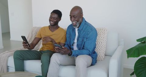Father and Son Sharing Moments on Smartphones in Cozy Living Room