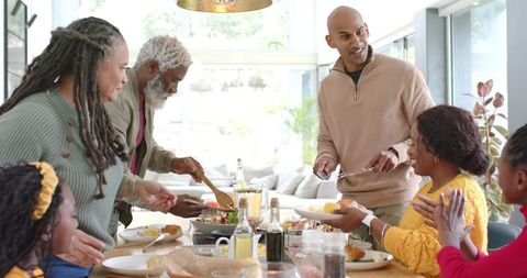Multigenerational Diverse Family Sharing Joyful Home-Cooked Dinner Around Sunlit Table