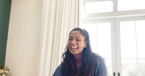 Laughing woman in bright living room with large windows