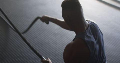 Focused Man Engaging in Intense Workout with Battle Ropes at Gym