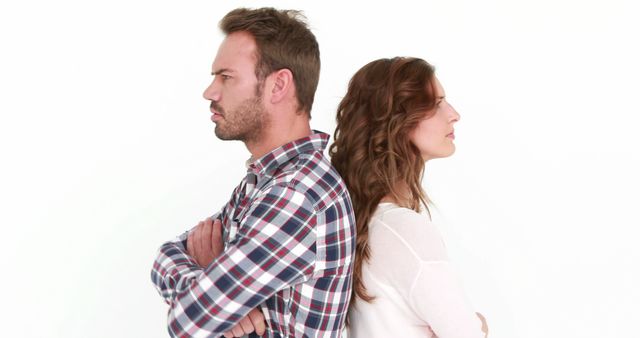 A Caucasian man and woman appear upset with each other, standing back-to-back with arms crossed, with copy space. Their expressions and posture suggest a disagreement or conflict that has yet to be resolved.